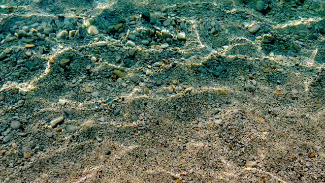 特写镜头。在爱琴海清澈的海水下，可以看到五颜六色的小鹅卵石。阳光，光线在水中反射视频素材