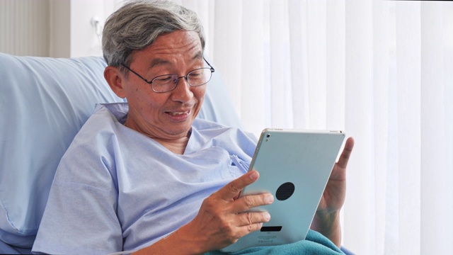 病人上了年纪的亚洲男子使用平板电脑享受他们在医院治疗期间。视频素材