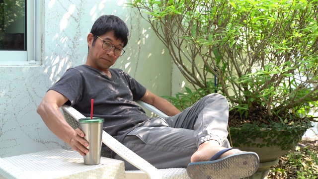 亚洲男人坐在花园里喝咖啡视频下载