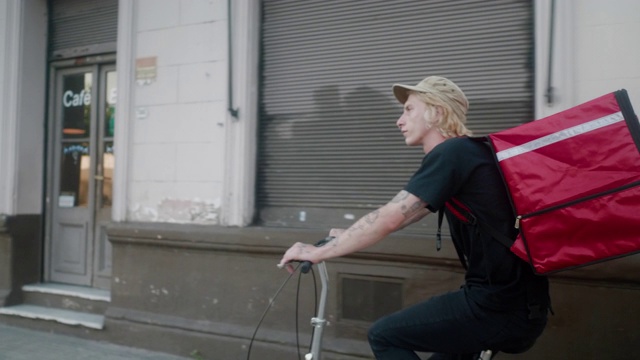 食品快递员骑着自行车在街上行驶视频下载