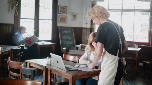 阿根廷女商人在餐厅吃午饭时在笔记本电脑后面工作视频素材