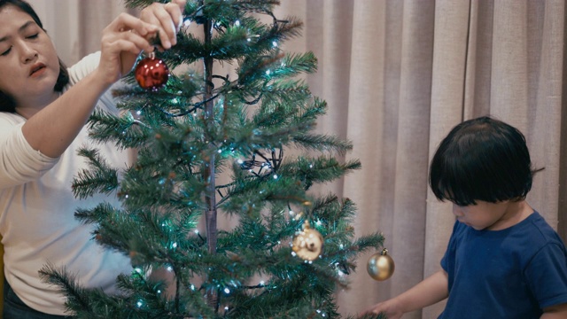 亚洲男孩和妈妈装饰圣诞树视频素材