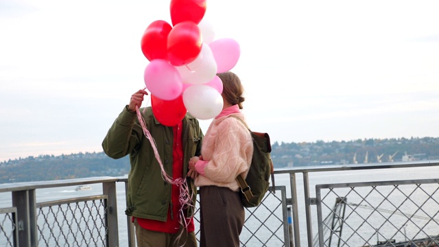 一对情侣在情人节约会时在心形气球后面接吻视频素材