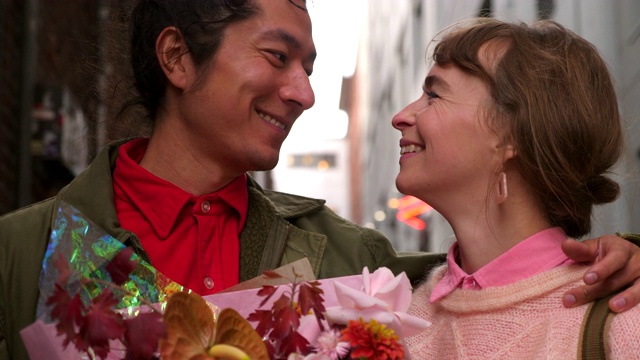 在约会探索城市时，拥抱情侣亲吻，手持一束鲜花视频素材