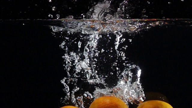 超级慢动作:橙色滴入淡水在黑色的背景视频素材