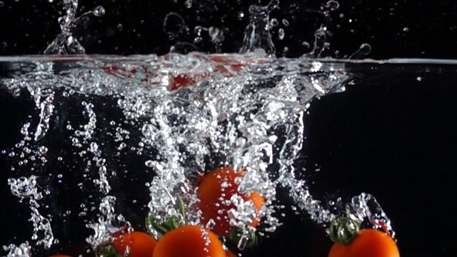 超级慢镜头:在黑色背景下，番茄掉进淡水中视频素材