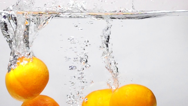 超级慢动作:橙色滴入淡水在白色的背景视频素材
