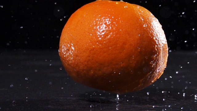 超级慢镜头:橙子掉在桌子上，水花四溅视频素材