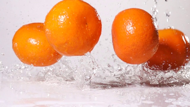 超级慢镜头:橙子掉在桌子上，水花四溅视频素材