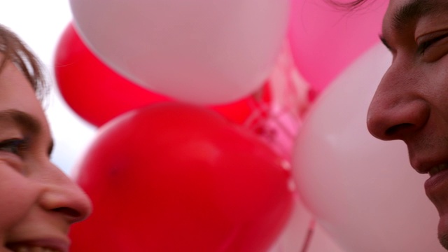 在情人节这天，一对情侣手捧气球亲吻视频素材