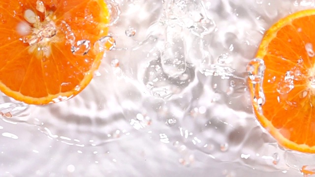 超级慢动作:橙子片落在水面上溅起水花视频素材