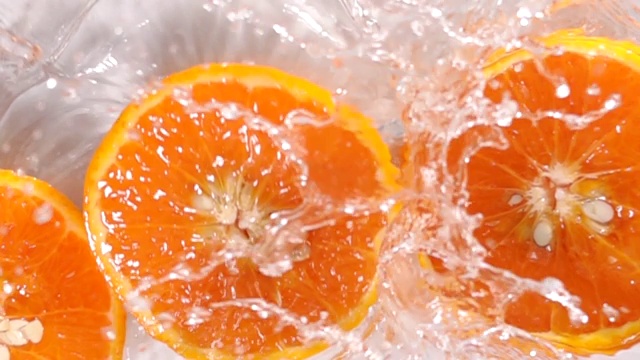 超级慢动作:橙子片落在水面上溅起水花视频素材