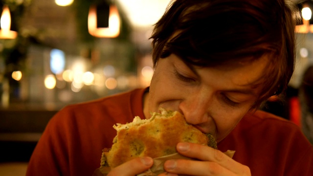 男人在橙色运动衫吃菠菜和奶酪面包特写视频下载