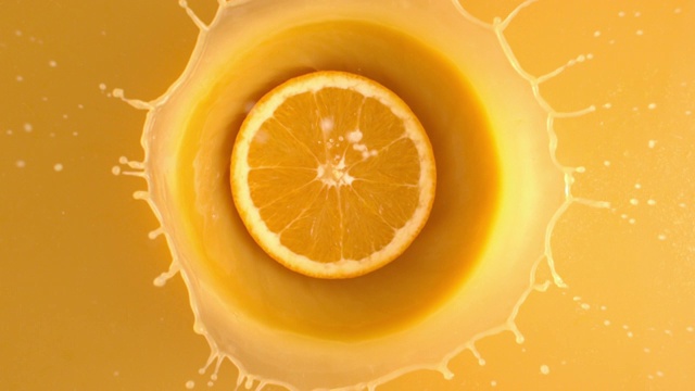 切片新鲜的橘子从上面扔到果汁与飞溅的慢动作视频下载