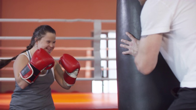 患有唐氏综合症的快乐女人和教练一起练拳击视频下载