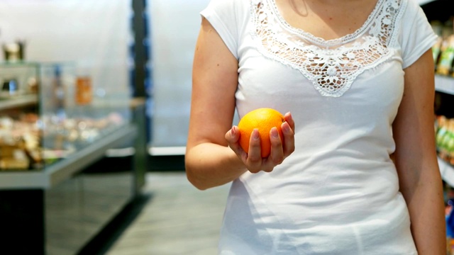 慢镜头中，女人的手在超市里抛出五颜六色的橙色视频下载