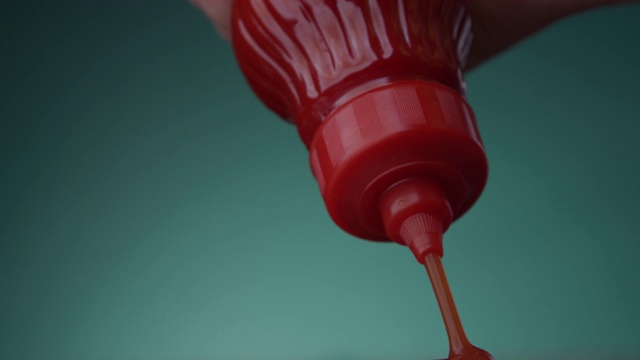 蕃茄酱从一个红色的瓶子挤压一个特写在一个比斯开绿色绿水Menthe颜色背景视频下载