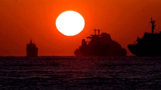-欧米茄形状的日出在Saengdo岛(水壶岛)/ yeongdo gu附近的渔船和货船上，釜山，韩国视频素材