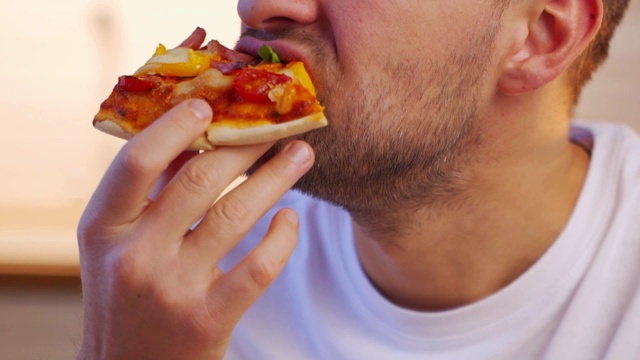 一个年轻漂亮的男人吃着一片披萨的肖像视频素材