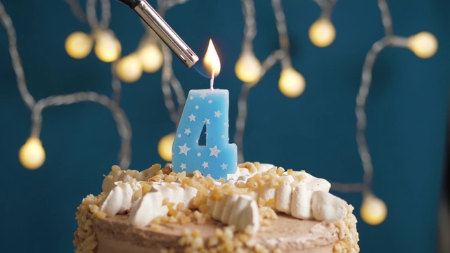 蓝底4号蜡烛生日蛋糕。蜡烛被点燃了。慢动作和近景视频素材