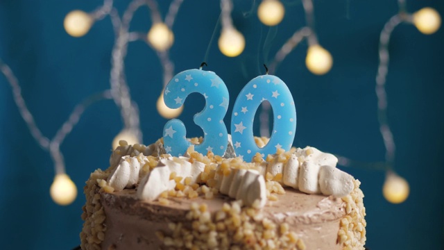 生日蛋糕与30号蜡烛在蓝色的背景。蜡烛吹灭。慢动作和近景视频下载