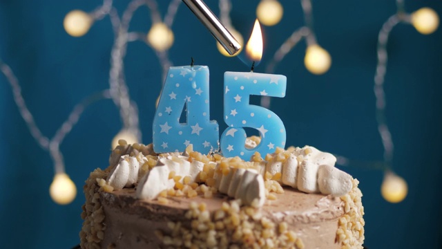 蓝底45号蜡烛生日蛋糕。蜡烛被点燃了。慢动作和近景视频素材