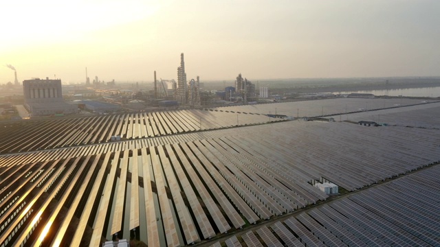 大面积太阳能发电厂鸟瞰图，远处有化工厂视频下载