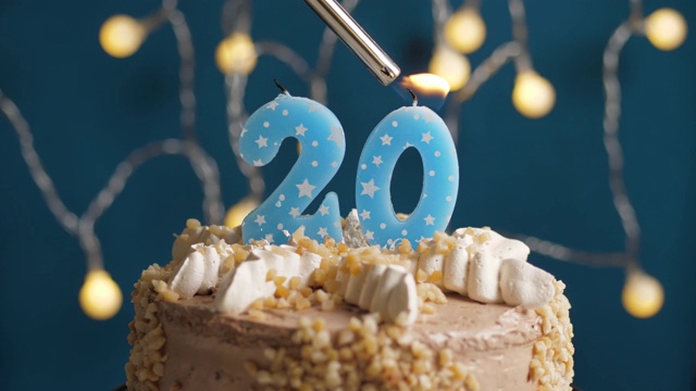 蓝底20号蜡烛生日蛋糕。蜡烛被点燃了。慢动作和近景视频素材