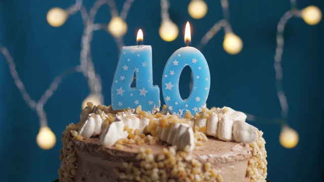 蓝底40号蜡烛生日蛋糕。蜡烛吹灭。慢动作和近景视频下载