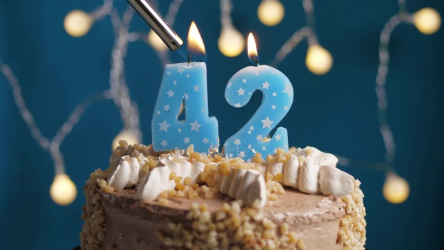蓝底42号蜡烛生日蛋糕。蜡烛被点燃了。慢动作和近景视频素材