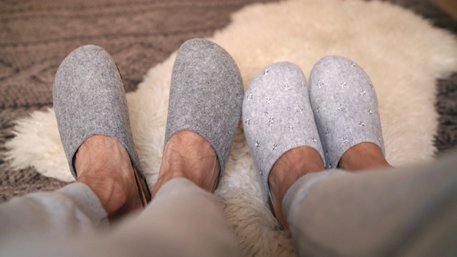 新买的两双灰色拖鞋上男女坐在床上脚搞笑移动在舒适的卧室里。家甜蜜家概念4K超高清电视镜头。视频素材