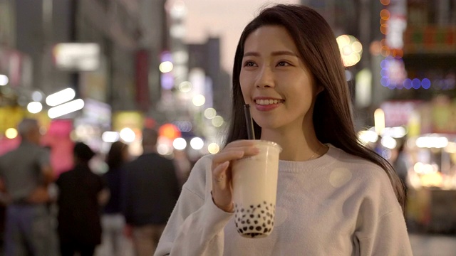 一名年轻女子喜欢在夜市吃珍珠奶茶和街头小吃视频下载