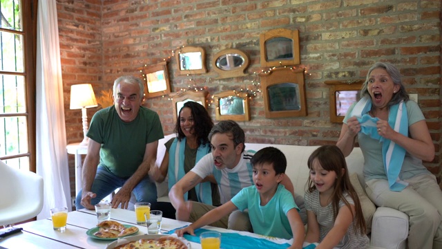 阿根廷家庭足球迷们兴高采烈，尖叫着吃着外卖披萨，看着足球比赛视频下载