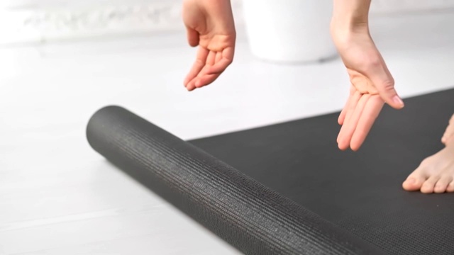 特写年轻健康的女人双手推出灰色瑜伽垫准备做早操在家视频素材