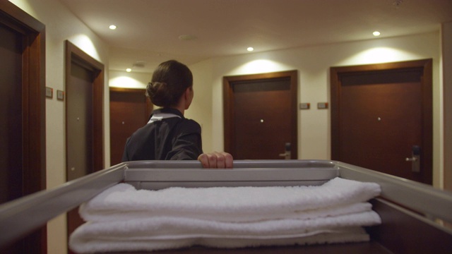后视图，客房服务员带着清洁设备穿过酒店走廊视频下载
