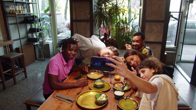 多文化的朋友坐在咖啡馆，女孩拍合影视频下载
