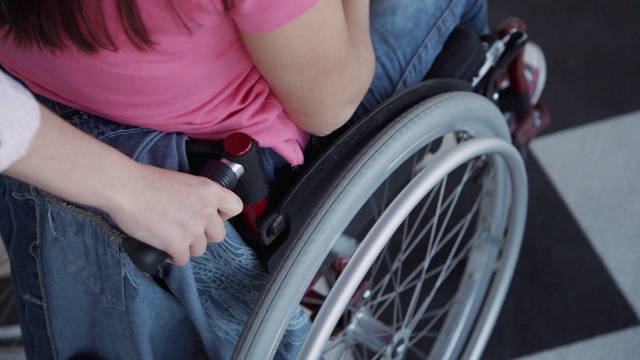 年轻女子帮助轮椅人骑在家里视频素材