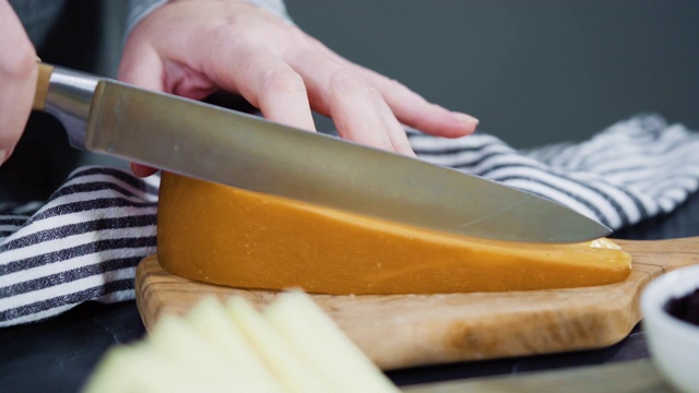 将美味的楔形奶酪在木板上切成小片。视频素材