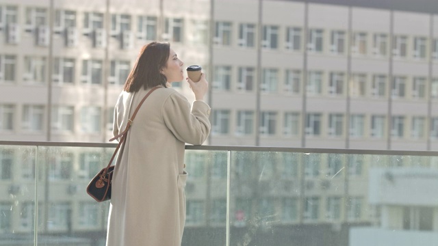 一个深思熟虑的白人女人喝着咖啡看向别处。成功的女商人在户外休息。电影4k ProRes总部。视频素材