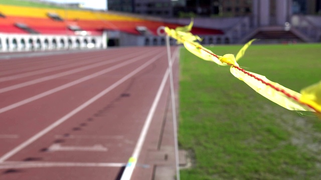 体育场的跑道。焦点是飘扬的黄旗。主题在右边。视频下载