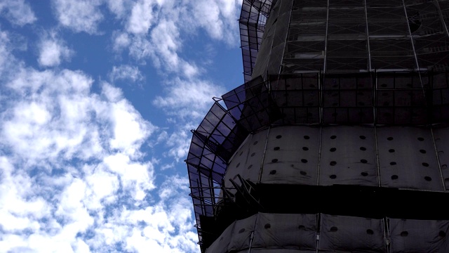 建筑工地。巨大的工业塔吊，背景是未完工的高耸建筑和蓝天。脚手架。现代土木工程。当代城市景观。主题在右边。视频素材