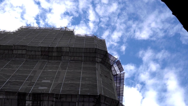建筑工地。巨大的工业塔吊，背景是未完工的高耸建筑和蓝天。脚手架。现代土木工程。当代城市景观。主题在左边。视频素材