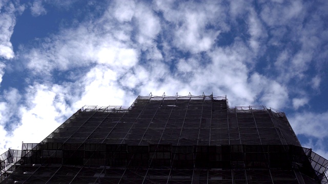 建筑工地。巨大的工业塔吊，背景是未完工的高耸建筑和蓝天。脚手架。现代土木工程。当代城市景观。视频素材