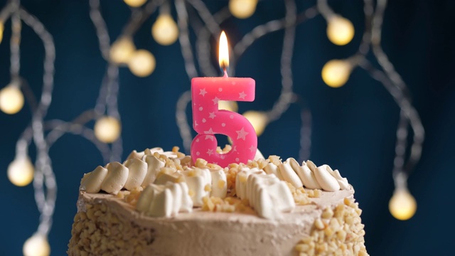 生日蛋糕与5号粉红蜡烛在蓝色的背景。蜡烛吹灭。慢动作和近景视频素材