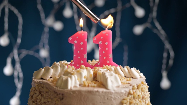 生日蛋糕与11号粉红蜡烛在蓝色的背景。蜡烛被点燃了。慢动作和近景视频下载
