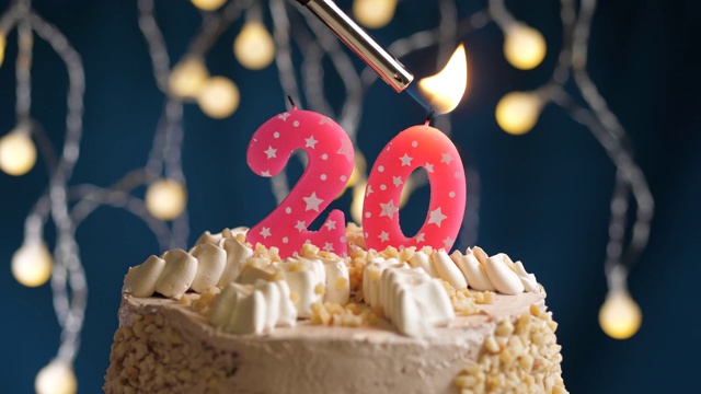 生日蛋糕与20号粉红蜡烛在蓝色的背景。蜡烛被点燃了。慢动作和近景视频下载