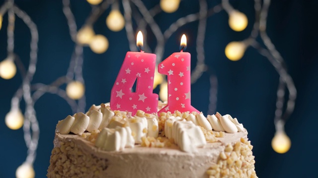 生日蛋糕与41号粉红蜡烛在蓝色的背景。蜡烛吹灭。慢动作和近景视频下载
