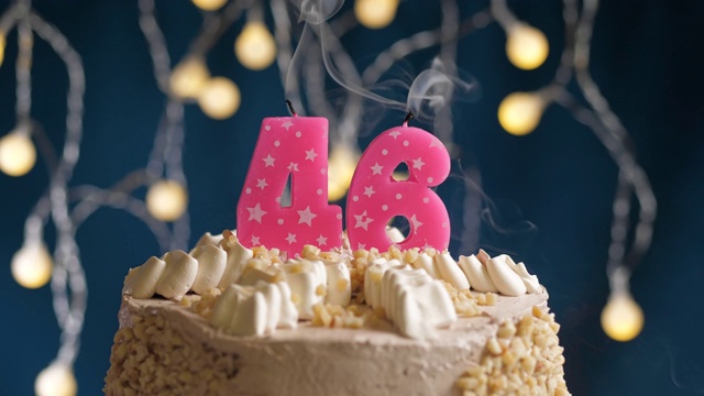 蓝底粉红蜡烛46号生日蛋糕。蜡烛吹灭。慢动作和近景视频下载