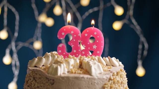 生日蛋糕与39号粉红蜡烛在蓝色背景。蜡烛吹灭。慢动作和近景视频下载