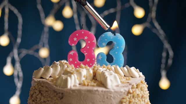 生日蛋糕与33号粉红蜡烛在蓝色的背景。蜡烛被点燃了。慢动作和近景视频下载